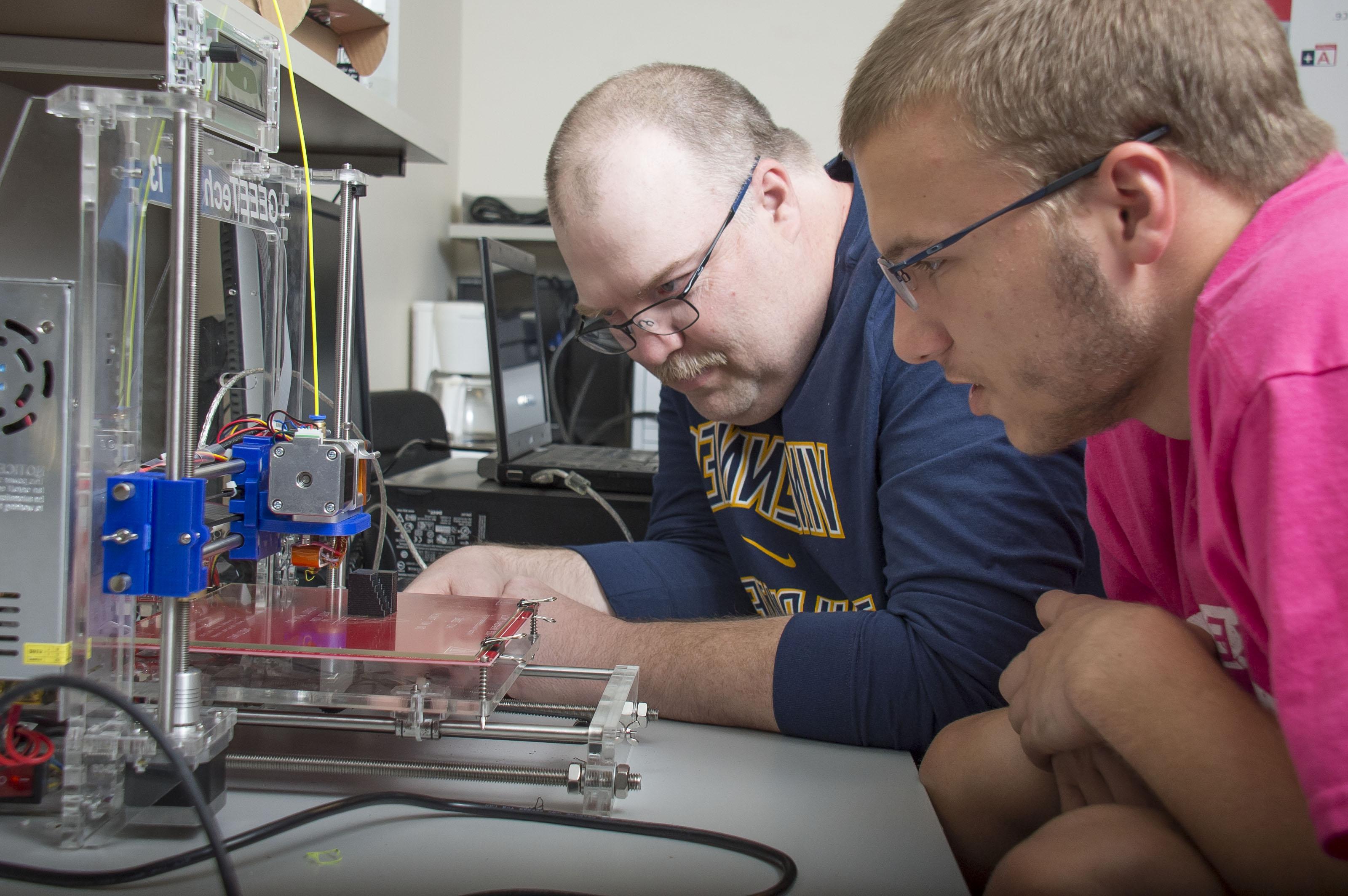 An electronics professor explaining how to use a 3D printer